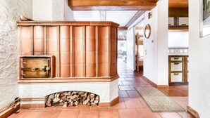 A stone fireplace with a tiled surround, a wooden ceiling, and a tiled floor. - Chalet Zentral Bach in Brand (Brand)