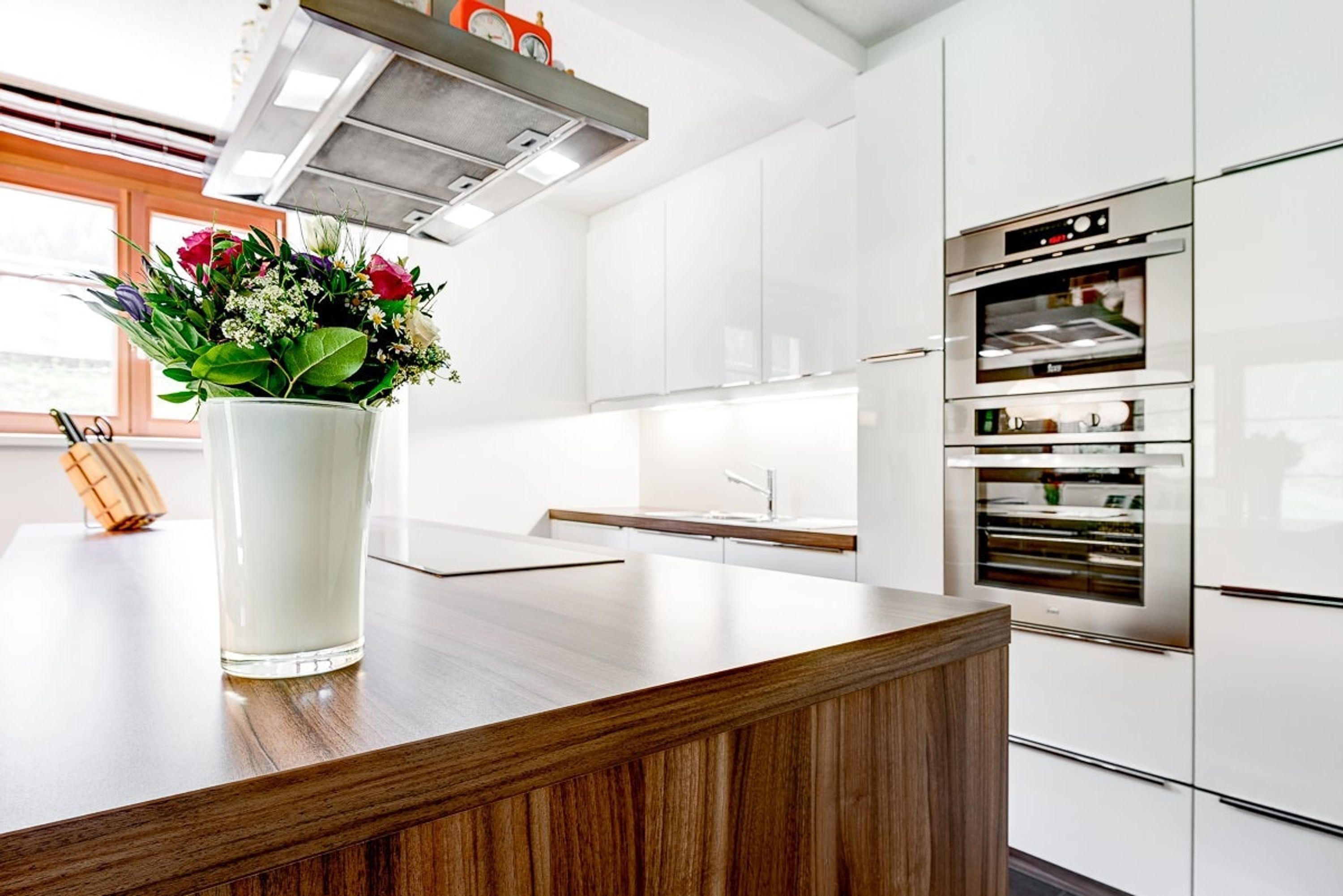 A modern kitchen with white cabinets, a wooden countertop, and a built-in oven.