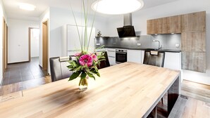 Une cuisine moderne avec une table à manger en bois, un vase rempli de fleurs et un luminaire suspendu.