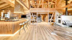 Ein geräumiger Holzinnenraum mit hoher Decke, einer zentralen Treppe, einer Bar und einer Sitzgelegenheit.