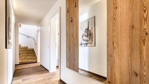 Een gang met houten vloer, een trap en een wand van houten panelen.