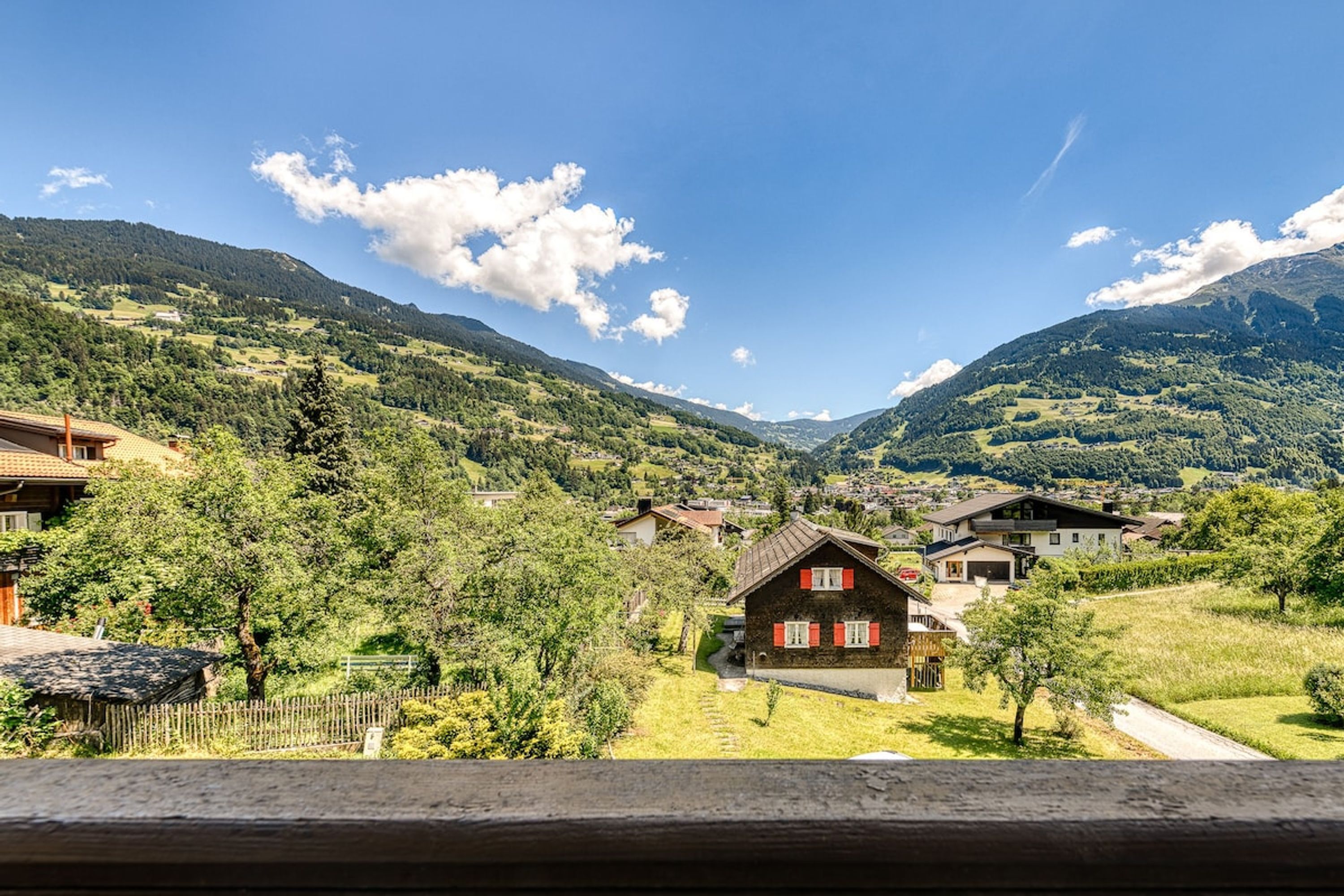 En landlig landsby med traditionelle huse, klar himmel og bjerge i baggrunden.