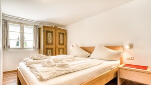 A bedroom with a wooden bed, a nightstand, a cabinet, and a window with curtains. - Chalet Mariedl in Tschagguns (Tschagguns)