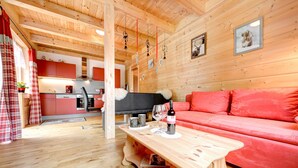 A wooden interior with a red sofa, a wooden coffee table, and a kitchen in the background. - Appartement Enzian in Brand (Brand)
