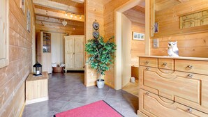 A wooden cabin interior with a central potted plant, wooden cabinets, and a dresser with a mirror. - Appartement Enzian in Brand (Brand)