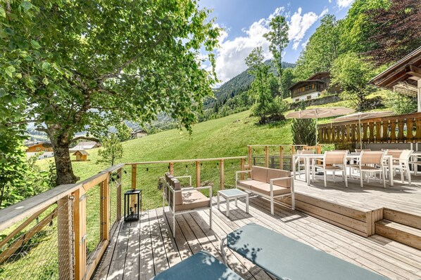 A wooden deck with outdoor furniture, a pool, and a scenic view of a mountainous area. - Haus Fellner in Brand (Brand)