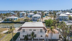 A coastal residential area with houses, a dock, and a body of water. - 21591 Spacious Right Waterfront 2BR| Heated Pool, Short Walk to Beach (Fort Myers Beach)