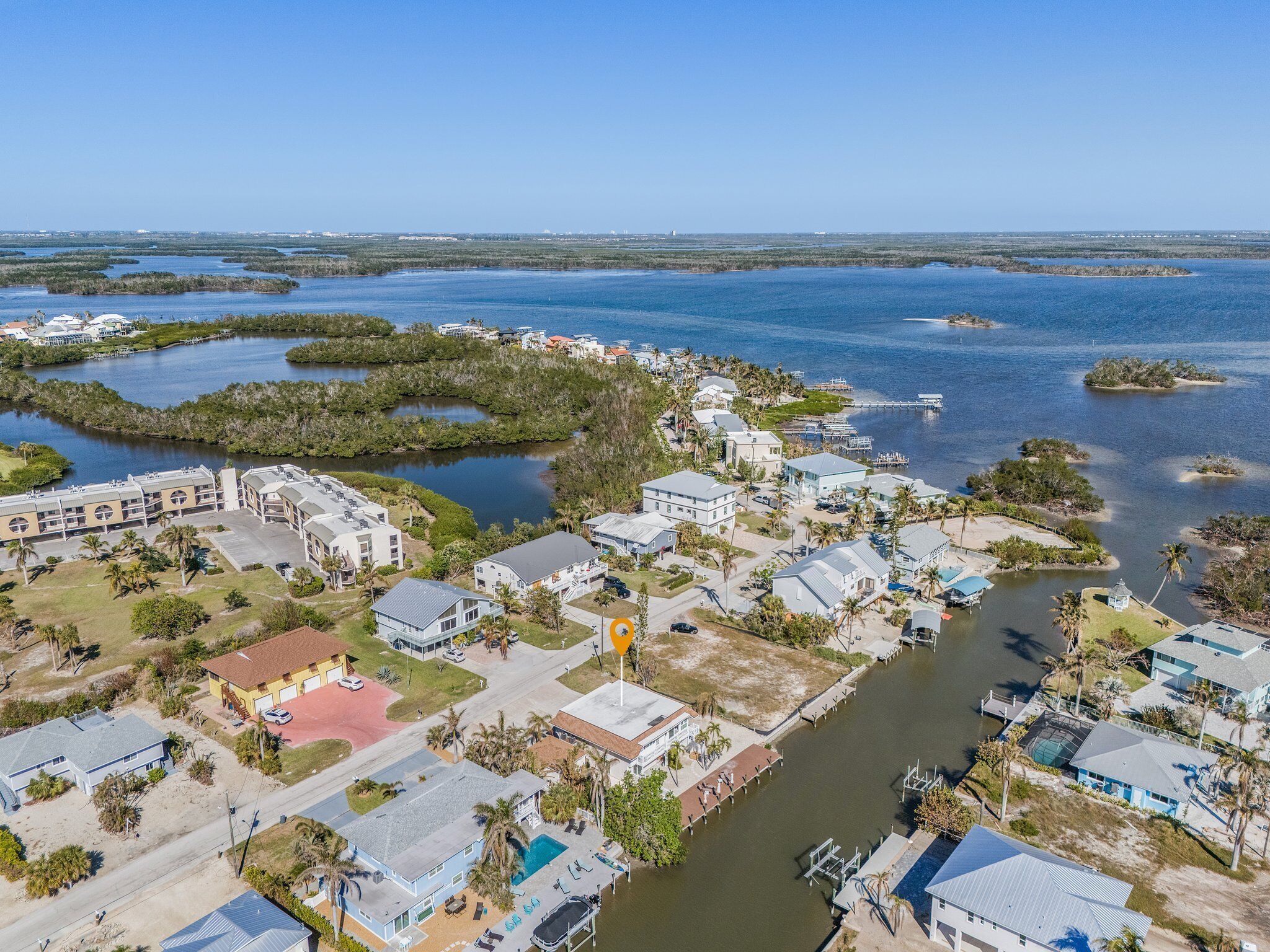 An aerial view of a coastal residential area with houses, a marina, and water bodies.