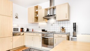 Una cocina moderna con armarios de madera, horno de acero inoxidable, microondas y cafetera.