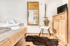 A bedroom with a wooden bed, a large mirror, a wooden wardrobe, and a fur rug on the floor. - Ferienwohnung Zweisamkeit (Brand)