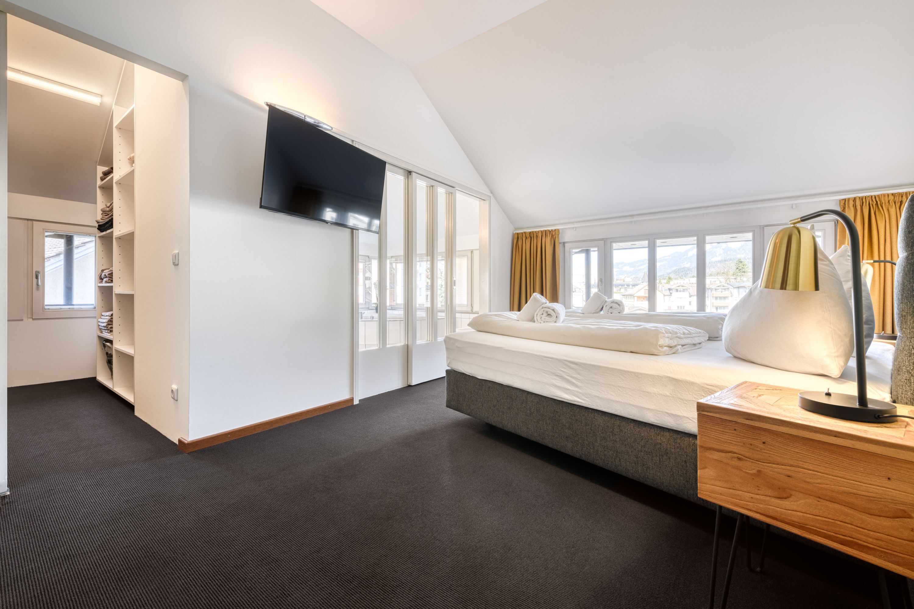 Een moderne hotelkamer met een groot bed, een bureau, een televisie en een kast met planken.