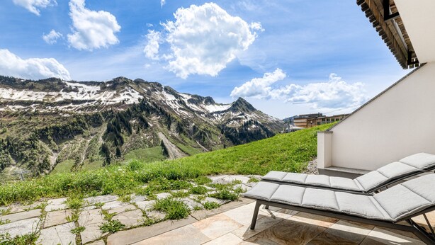 Una silla de descanso en un patio de piedra con vista a la montaña.
