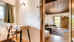 Una habitación con un escritorio de madera, una silla y una cama con un tapete rojo y negro estampado.