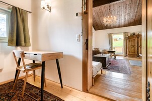 Una habitación con un escritorio de madera, una silla y una cama con un tapete rojo y negro estampado.