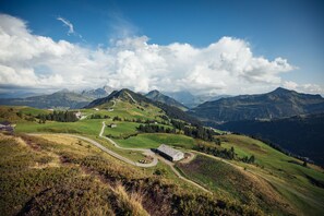 A mountainous landscape with a winding road, a building, and distant mountains. - Haus H Mmerle mit Ski in - Ski out (Damüls)