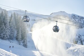 A ski lift with cabins, snow-covered trees, and a mountain backdrop. - Haus H Mmerle mit Ski in - Ski out (Damüls)