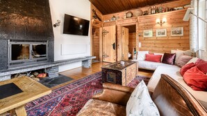 Una sala de estar acogedora con chimenea, paredes de madera, un sofá y una mesa de centro.
