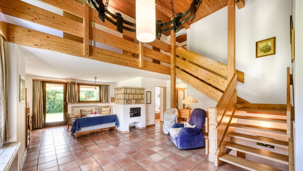 A spacious living area with a high wooden ceiling, a fireplace, a sofa, and a chair. - Ferienhaus Haas in Vandans (Vandans)