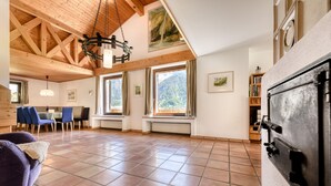 A spacious living area with a high ceiling, large windows, and a fireplace. - Ferienhaus Haas in Vandans (Vandans)