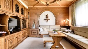 A room with a wooden cabinet, a television, a sofa, a table, and a decorative wall piece. - Landhaus Bergblick in Ludesch (Ludesch)