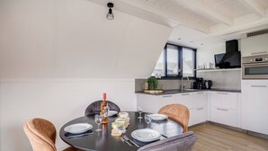 A modern kitchen with white cabinets, a built-in oven, and a window with blinds.