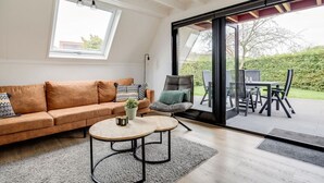 A modern living room with a sofa, coffee table, and a view through a glass door to an outdoor patio area.