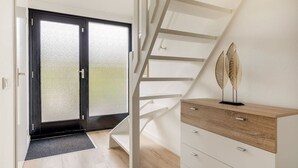 A modern interior with a staircase, a wooden cabinet, and a glass door leading to a balcony.