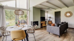 A spacious living area with a dining table, chairs, a sofa, and a TV. - Braamsluiper | Vakantiewoning met grote zonnige tuin (Zwiggelte)