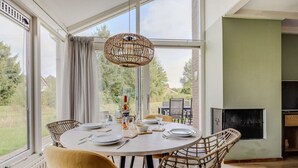 A dining area with a round table set for four, surrounded by wicker chairs. - Braamsluiper | Vakantiewoning met grote zonnige tuin (Zwiggelte)