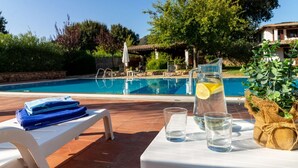 Een zwembadterras met een tafel, een glazen waterkan met een citroenpartje en een waterfles.