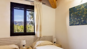 Een slaapkamer met twee bedden, een raam met uitzicht op het landschap en een schilderij aan de muur.