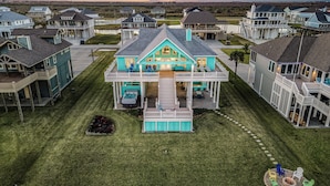 A large two-story house with a balcony, surrounded by a well-maintained lawn and a fire pit.