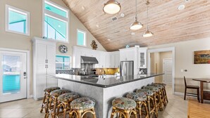 A spacious kitchen with a large island, bar stools, and a dining area with a wooden table and chairs.