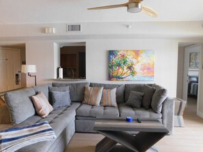 A modern living room with a sectional sofa, a coffee table, and a ceiling fan.