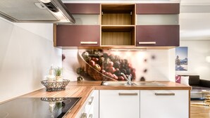 A modern kitchen with wooden cabinets, a built-in stove, and a large window above the sink. - Ferienwohnung R ti - 2-zimmer mit Sw-balkon (Brand)
