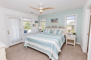 A bedroom with a bed, a nightstand, a ceiling fan, and a window. - Oceanside, Pool, Hot Tub, Rec Room, Close to Beach -WC920, Whalehead Retreat (Corolla)