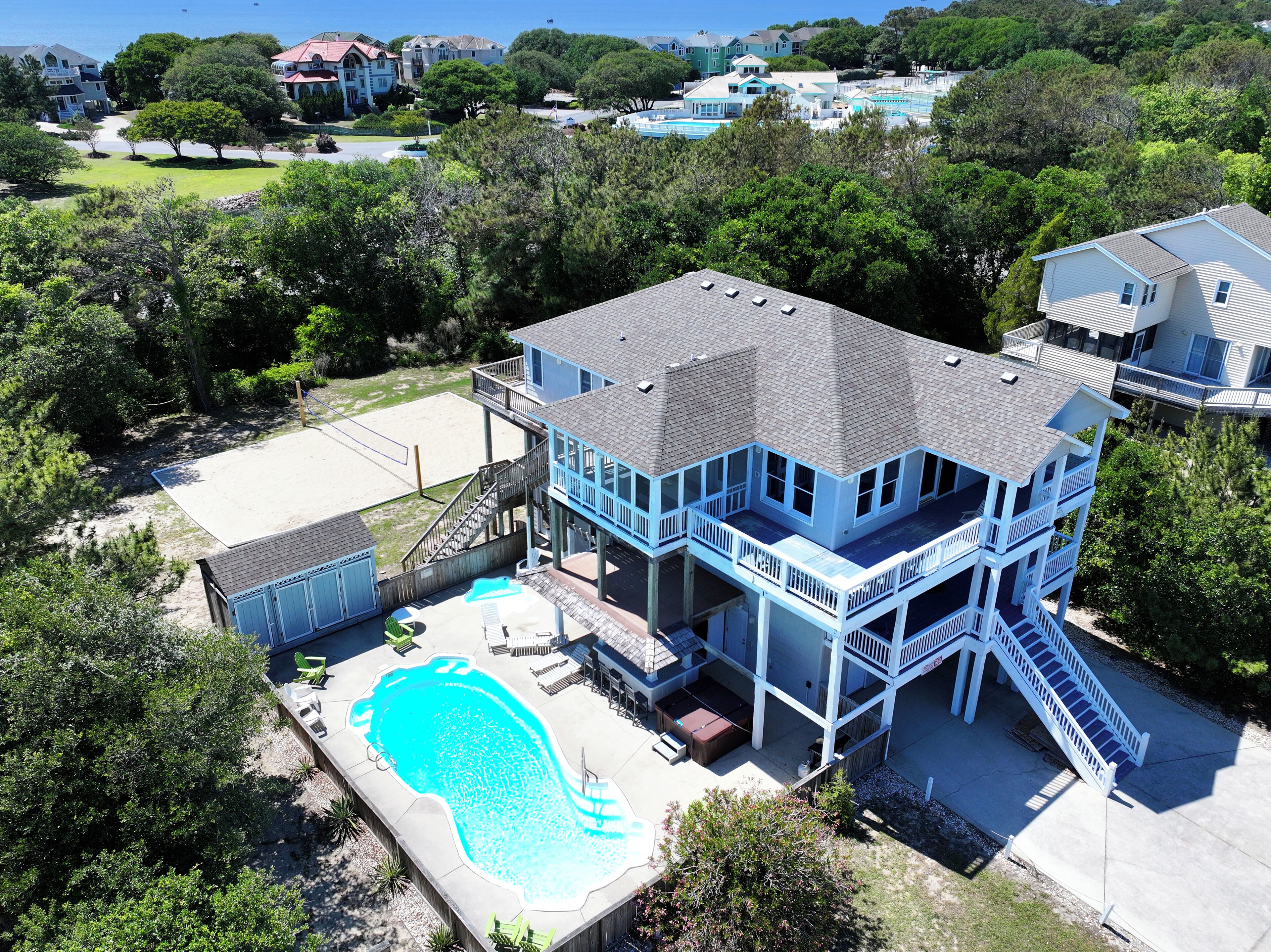 Une grande maison avec une piscine, plusieurs balcons et une terrasse.