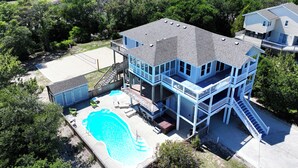 A large house with a swimming pool, multiple balconies, and a deck area.