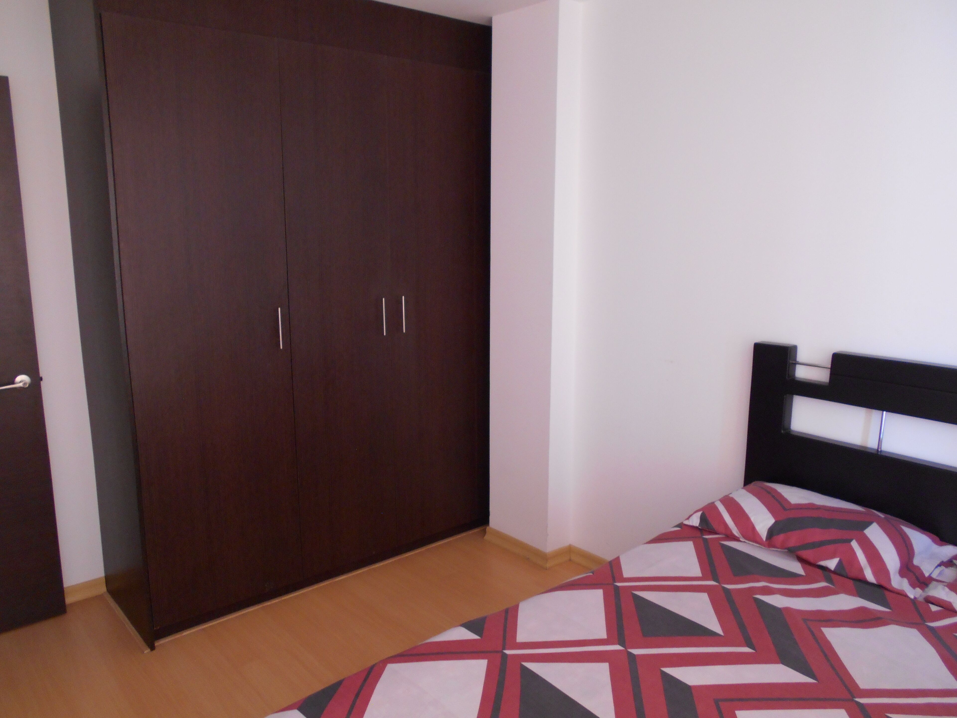 A bedroom with a bed, a wardrobe, and a door.