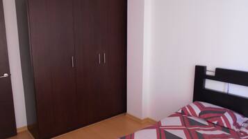 Quarto com uma cama, um guarda-roupa e uma porta.