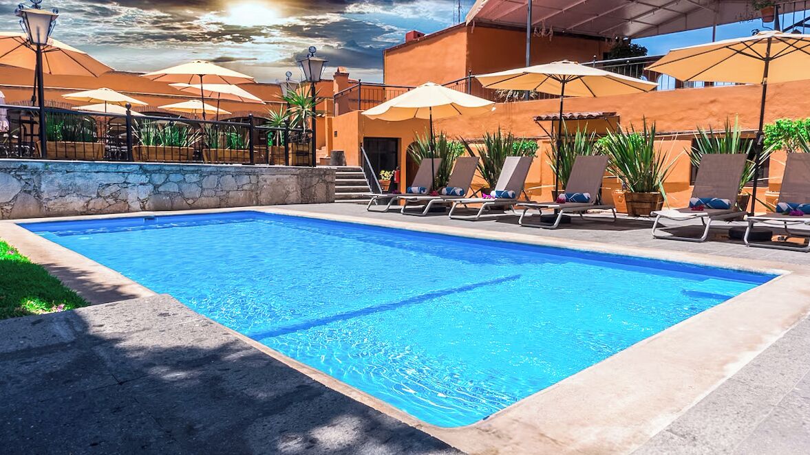 Una piscina al aire libre, sombrillas, sillones reclinables de piscina