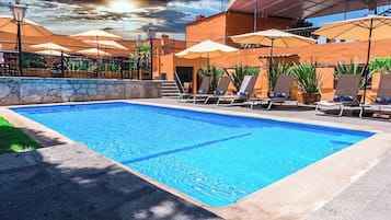 Una piscina al aire libre, sombrillas, sillones reclinables de piscina