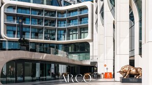 Un bâtiment moderne doté de nombreux balcons, de grandes fenêtres et d’une sculpture imposante représentant un taureau.