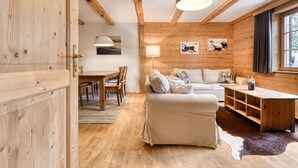Un accogliente interno di una baita con pareti in legno, un'area pranzo, un divano e un tavolino da caffè.