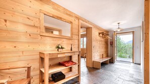 Un interno in legno con pavimento in pietra, arredi in legno e vista attraverso una porta.