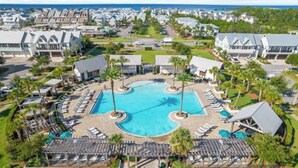 Un complexe hôtelier doté d’une piscine centrale, de chaises longues et de palmiers.