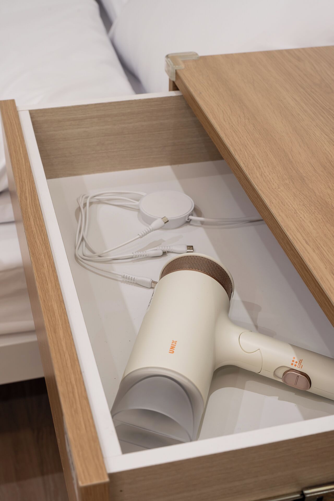 A drawer containing a hair dryer and its accessories.