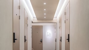 Un couloir d’hôtel avec un sol recouvert de moquette, des portes en bois et une pancarte sur laquelle on peut lire : « RESTEZ SAI ».