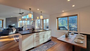 A modern kitchen with a central island, large windows, and a dining area. - Hot tub | Sauna |Firepit |Sleeps 6! (Ashland)