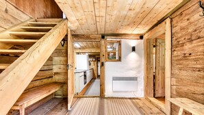 A wooden interior with a staircase, a kitchen area, and a white wall with a vent. - Berghaus Lutzklang in Raggal (Raggal)